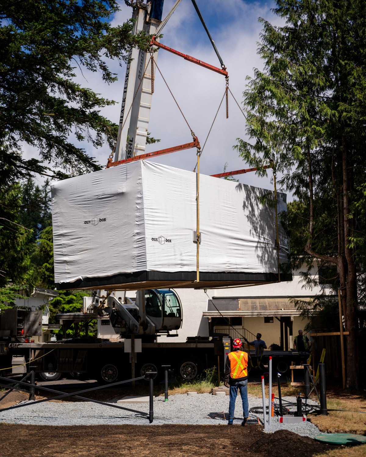 Modular ADU lifted into a backyard by crane